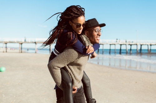 Teenagers playing piggy back on the beach