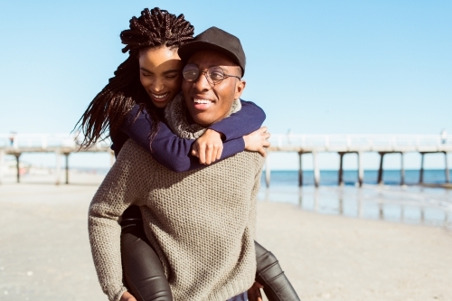 Teenagers playing piggy back on the beach - Australian Stock Image