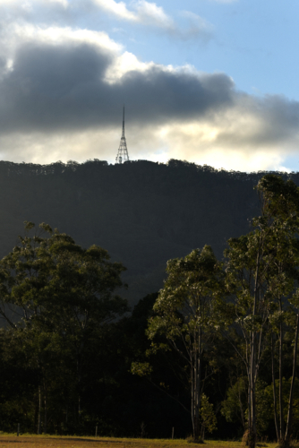 telecommunications tower on a hill in the distance, trees, clouds, blue sky - Australian Stock Image