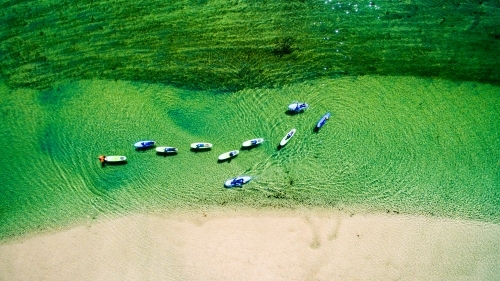 Ten paddle boarders on Cudgera Creek at Hastings Point from above
