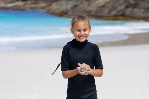 ten-year-old in black springsuit on beach - Australian Stock Image