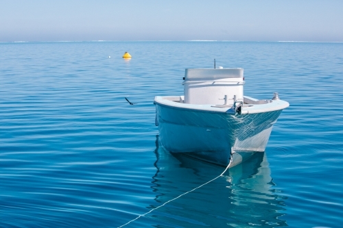 Tender jet boat on its mooring on a calm blue ocean - Australian Stock Image