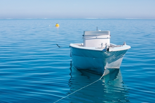 Tender jet boat on its mooring on a calm blue ocean