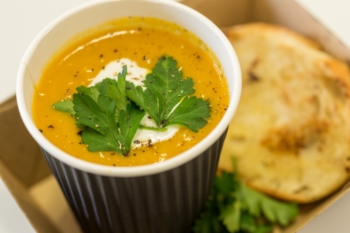 Thai Pumpkin soup served with bread in a takeaway box - Australian Stock Image
