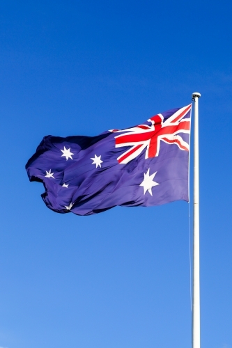 The Australian Flag waving proudly under a clear blue sky