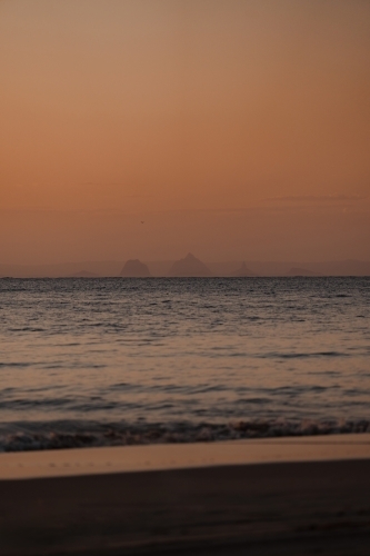 The Glasshouse Mountains visible from Moreton Island at sunset - Australian Stock Image
