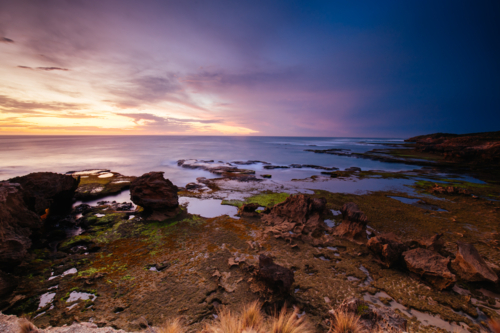 The idyllic Pearses Beach and headland around Pirates Bay Cove on a hot summer's evening. - Australian Stock Image