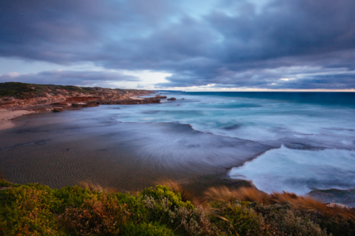 The idyllic Pearses Beach and headland around Pirates Bay Cove on a hot summer's evening - Australian Stock Image