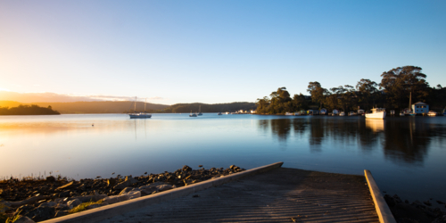 The idyllic setting across Wagonga Inlet at sunset in Narooma, NSW, Australia - Australian Stock Image