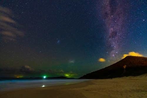 The Milky Way galaxy in the night sky over a coastal mountain at the end of a beach - Australian Stock Image