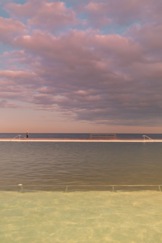 The Newcastle Ocean Baths at dusk with pink and purple fairy floss sky - Australian Stock Image