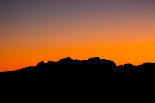 The silhouette of the boulders of the Olgas at sunset on a clear winter's evening in NT - Australian Stock Image