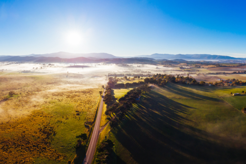 The sun rises through fog on a cold autumn morning near Yarra Glen in the Yarra Valley, Victoria - Australian Stock Image