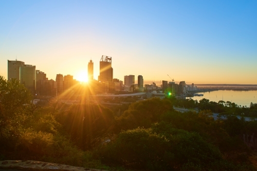 The sun rising above the Perth City skyline as seen from King's Park on a misty morning.