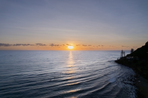 The sunrise over the ocean with  paddle boarders waiting for the waves - Australian Stock Image