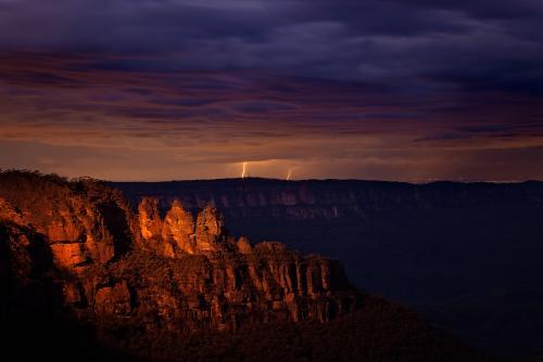 The Three Sisters at night with lightning bolts