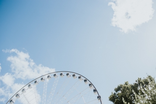 The top of a ferris wheel and tree against  the sky - Australian Stock Image