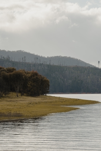 The water's edge with mountains in the background at Blowering Reservoir - Australian Stock Image