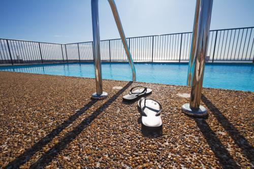 Thongs on pebble mix swimming pool edge - Australian Stock Image