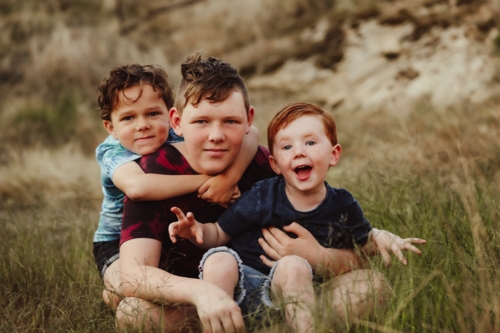 Three brothers sitting together on a rock in the Australian bush - Australian Stock Image