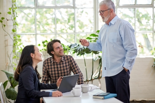 Three business people chatting, working in a studio office - Australian Stock Image
