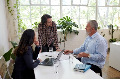 Three business people talking, sharing ideas in studio office - Australian Stock Image
