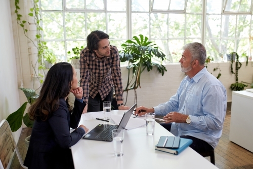 Three business people talking, sharing ideas in studio office