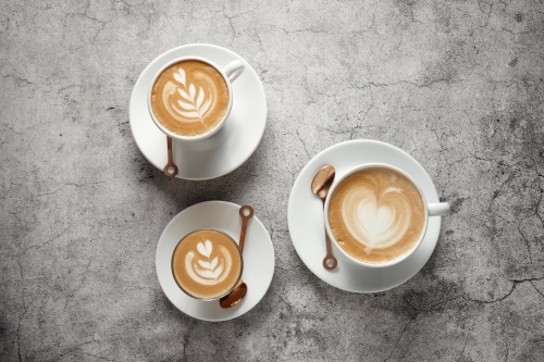 Three coffees on saucers with teaspoons - Australian Stock Image