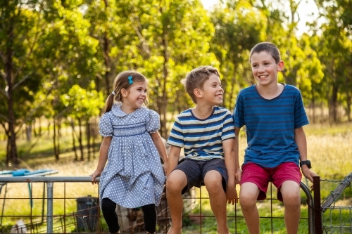 Three happy children laughing together outside - Australian Stock Image