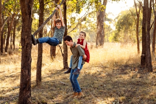Three happy siblings playing together on country farm in Australia in winter - Australian Stock Image