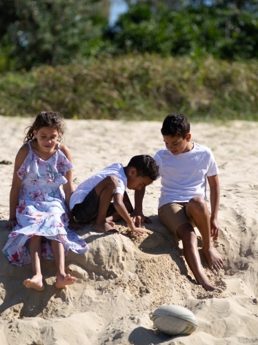 Three indigenous children playing in the sand