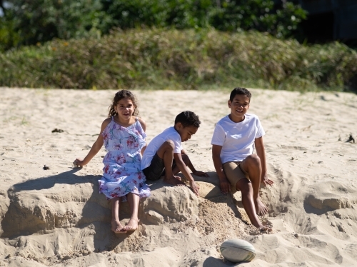Three indigenous children playing in the sand