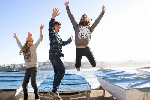 Three kids excitedly jumping in the air off a boat