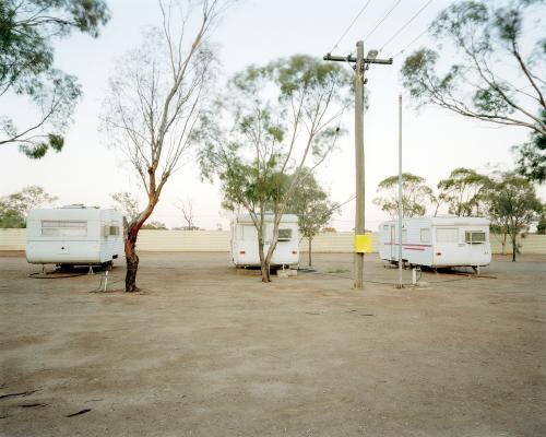Three old caravans parked in dusty, remote caravan park
