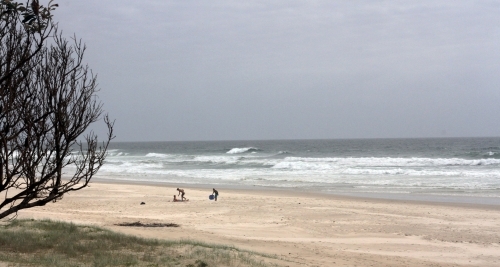 Three people playing on the beach on an overcast day