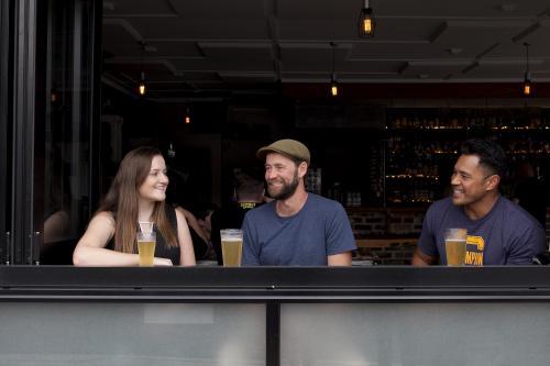 Three people sitting having a drink at a local craft beer bar - Australian Stock Image