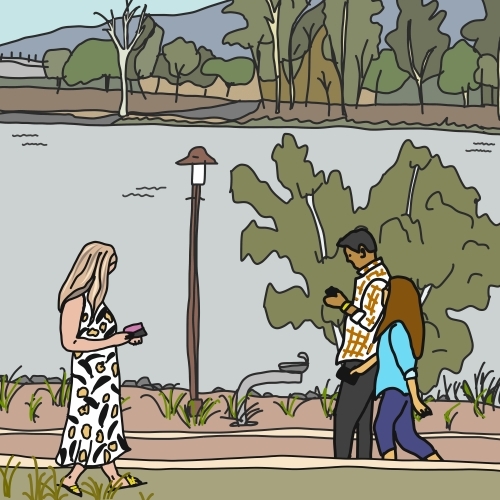 Three people walking along riverside path looking at mobile phones