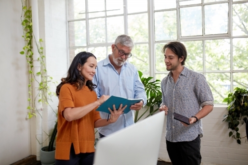 Three professional business people, sharing ideas in a studio office - Australian Stock Image