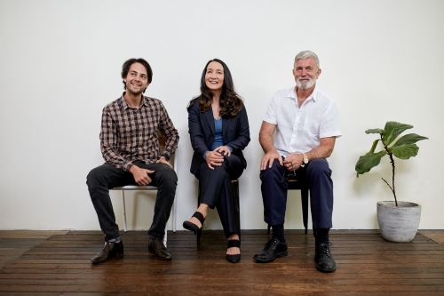 Three professional business people sitting in a row in a studio