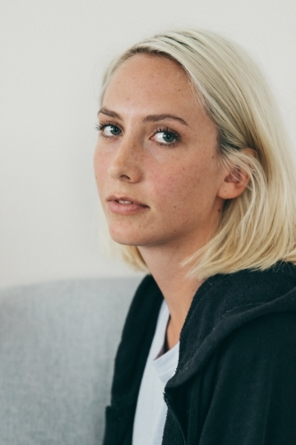 Three quarter profile of young blonde woman in hoodie and tshirt - Australian Stock Image