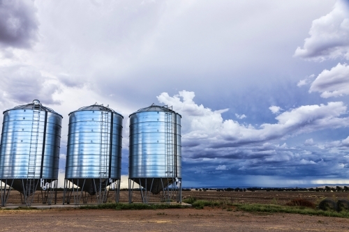 Three silos and farm land with storm clouds
