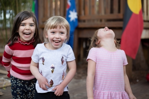 Three young girls laughing together at preschool