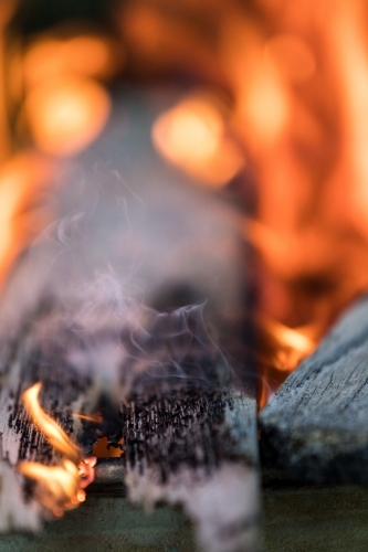 Timber plank smoldering with smoke and fire