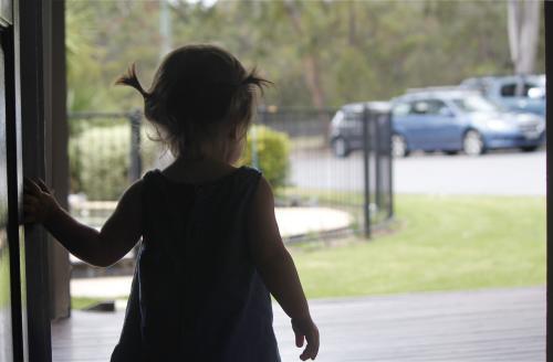Toddler at walking out the front door of a house - Australian Stock Image