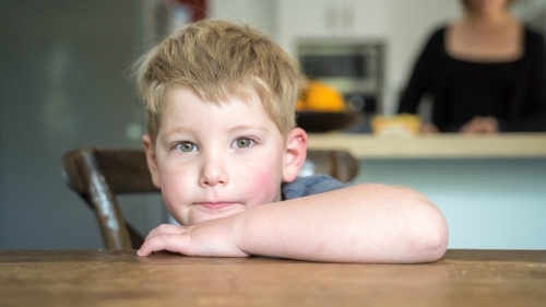 Toddler boy leaning on table inside home - Australian Stock Image