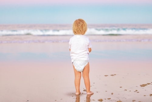 Toddler boy playing on the beach at sunset while on vacation on the Gold Coast in Queensland - Australian Stock Image