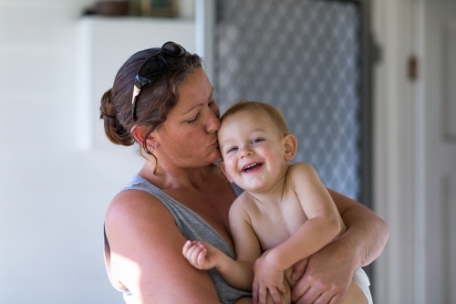 Toddler giggling in mother's arms - Australian Stock Image
