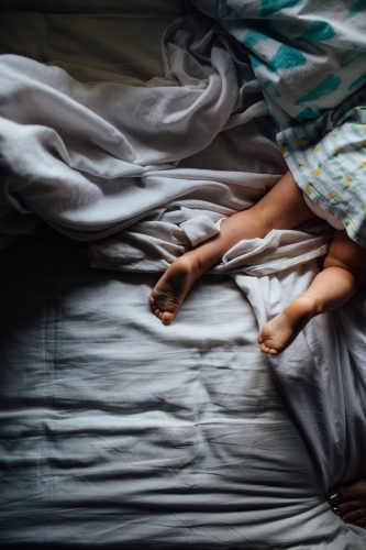 Toddler girl playing on bed - Australian Stock Image