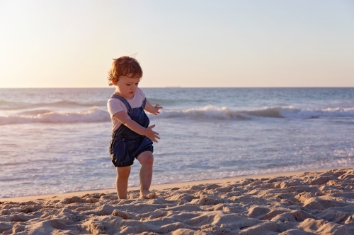 Toddler Girl Running On The Beach At Sunset