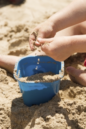 Toddler hands playing with sand at the beach - Australian Stock Image
